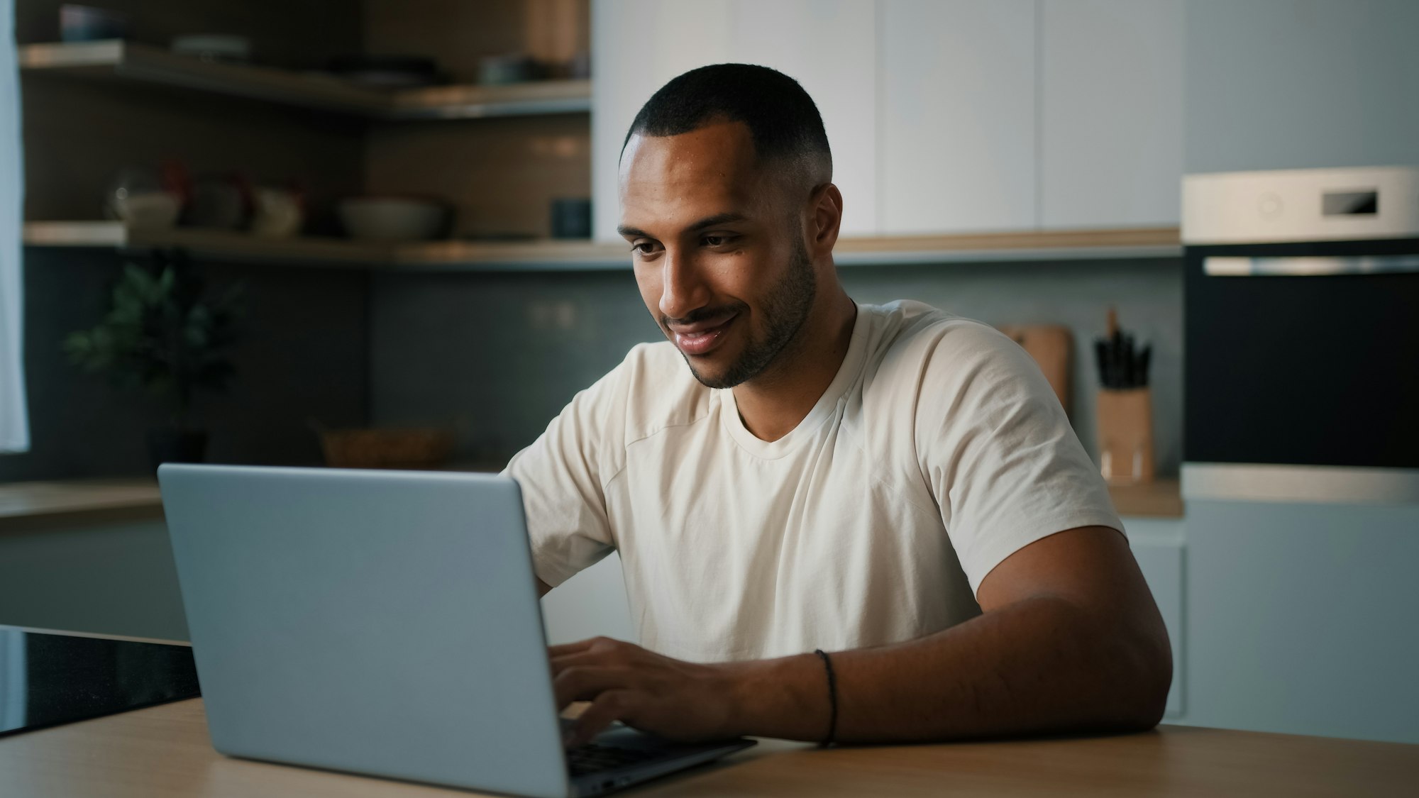 Smiling African millennial man guy American male user freelancer at home kitchen finish distant work